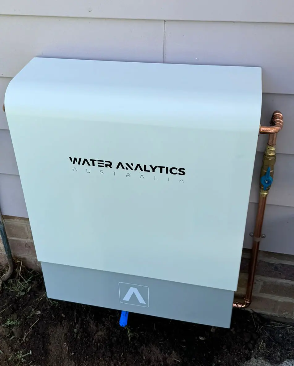 White and grey Water Analytics filtration unit mounted to brick wall